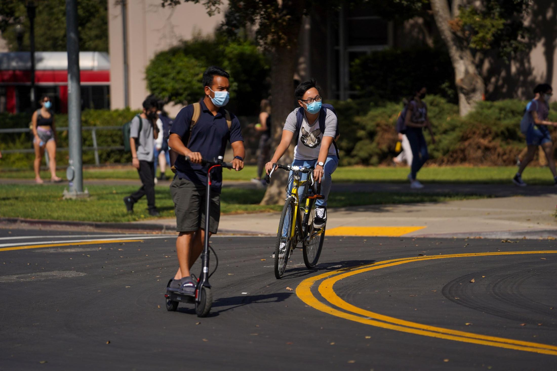 Students riding a scooter and bike